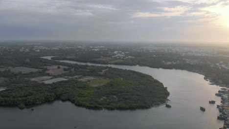 Aerial-Truck-shot-of-a-land-area-covered-by-a-river-on-one-side-and-ocean-on-the-other-side-near-Pondicherry-Harbor,-shot-with-a-drone-in-4k
