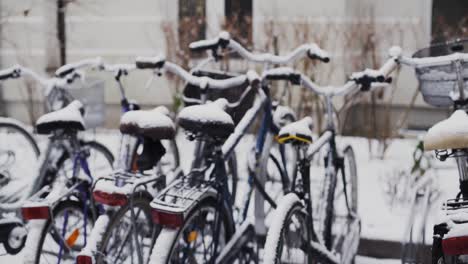 Nieve-Cayendo-Sobre-Un-Grupo-De-Bicicletas-Urbanas-Estacionadas-En-El-Portabicicletas-En-Invierno