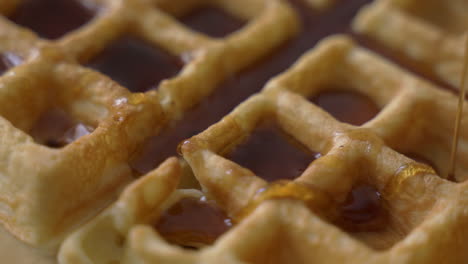 Rotating-up-close-macro-view-of-crisp,-golden-waffles-being-drizzled-with-sweet-maple-syrup