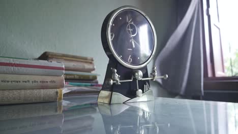 Table-clock-with-pendulum-at-morning,-books-on-table