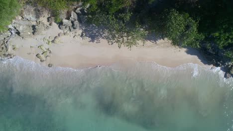Upward-drone-shot-on-beautiful-beach-with-splashing-waves,-white-sand,-turquoise-blue-water,-sunny-day