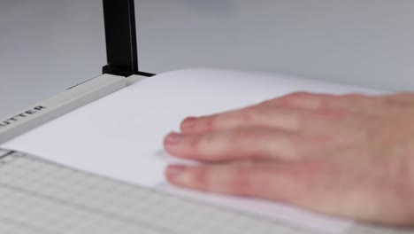 Person-cutting-an-A4-piece-of-paper-into-A5-using-a-guillotine-style-paper-cutter