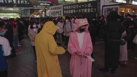 Dos-Personas-Vestidas-Con-Trajes-De-Pokemon-Amarillos-Y-Rosados-En-La-Noche-De-Halloween-En-La-Estación-De-Shibuya,-Tokio,-Japón---Cámara-Lenta