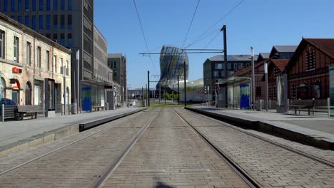 Cité-du-Vin-tram-stop-with-the-museum-in-the-distance-during-the-COVID-19-pandemic,-Locked-low-angle-shot