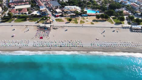 Aufnahme-Eines-Panoramas-Der-Strandlinie-Mit-Sonnenschirmen-Und-Liegestühlen-Im-Mittelmeer-In-Der-Türkei-Aus-Einer-Drohne