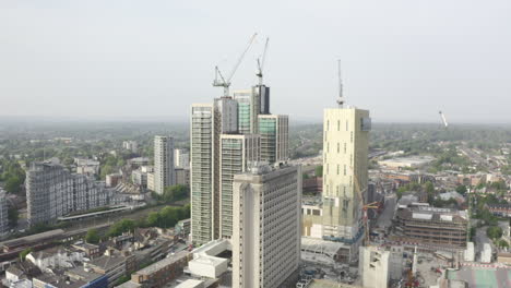 Drone-Aerial-shot-of-Woking-Cityscape-a-town-in-England-with-high-rise-skyscrapers-and-cranes-building-works-with-drone-tracking-backwards