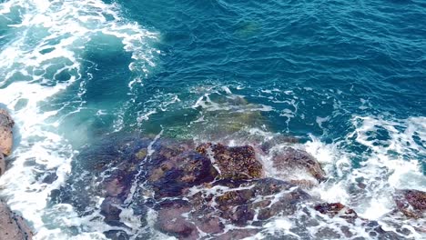 HD-Hawaii-Kauai-slow-motion-static-wide-shot-of-ocean-waves-swirling-around-rocks-in-lower-frame-with-sea-turtle-surfacing-in-center-top-of-frame