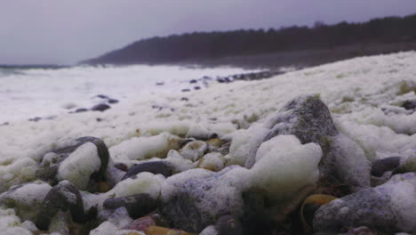 Dirty-Yellow-Foam-Or-Bubbles-Left-On-The-Rocky-Shore,-Thrown-By-The-Strong-Waves-On-Skagerak-Coast-In-Arendal,-Norway