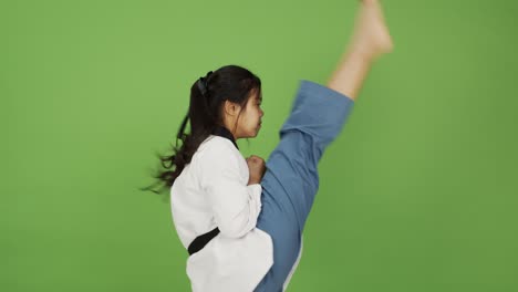 Junge-Asiatische-Frau-Zeigt-Kampfkunst-Expertenbewegungen-Mit-Grünem-Hintergrund---Zeitlupe