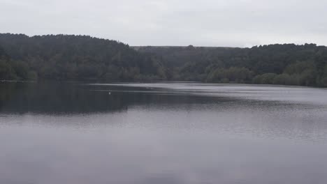 Reservoir-in-Yorkshire-expanse-of-water-with-trees-wide-panning-shot