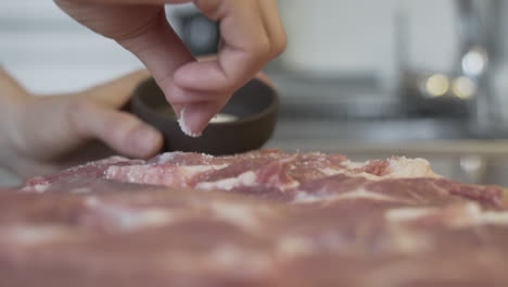 Close-up-selective-focus-shot-as-applying-salt,-putting-salt-to-a-piece-of-raw-meat