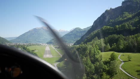 Aerial-view-of-abandoned-airport-between-mountains,-small-private-plane-landing-on-runway