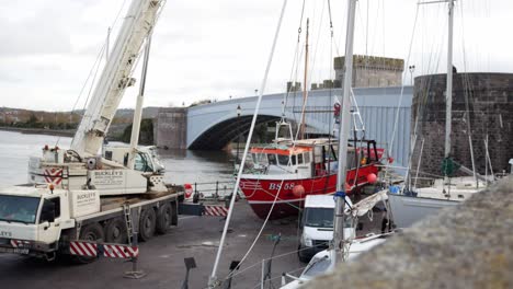 Hydraulic-crane-vehicle-lifting-fishing-boat-vessel-on-Conwy-Wales-harbour