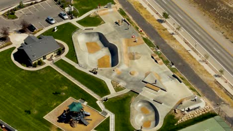 Static-aerial-view-of-a-skate-park-with-kids-having-fun-in-summer---slow-motion