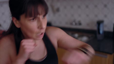 Mujer-Tomando-Clases-De-Boxeo-Físico-En-Línea-En-Casa,-En-La-Cocina