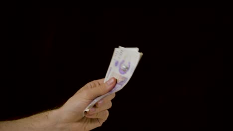 Hand-waving-a-neat-stack-of-cash-money-constantly-against-a-black-background-in-slow-motion