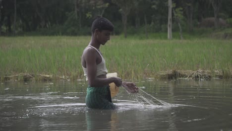 Ein-Fischer-Aus-Dem-Norden-Bangladeschs-Zieht-Sein-Netz-Im-Seichten-Wasser,-Um-Nach-Fischen-Zu-Suchen