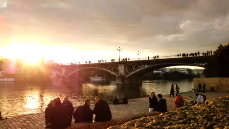 Goldener-Sonnenuntergang-Im-Zeitraffer-Mit-Menschen-An-Der-Triana-Brücke-In-Sevilla,-Spanien