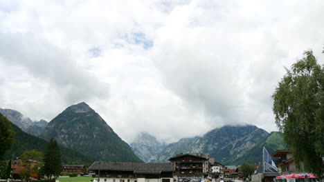 Beautiful-mountain-panorama-in-austrian-Alps-with-people-visiting-Pertisau-city-at-Achen-lake-during-cloudy-day