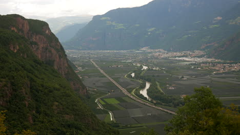 Paisaje-Rural-De-Montañas-En-Italia,-La-Autopista-Del-Brennero,-El-Río-Etsch-Y-La-Ciudad-De-Bolzano-Al-Fondo.