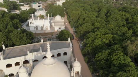 Aerial-Over-White-Mosque-Surrounded-By-Green-Trees-In-Karachi