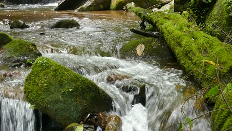 Water-rushes-over-moss-covered-rocks-in-the-foreground-in-a-peaceful-relaxing-scene