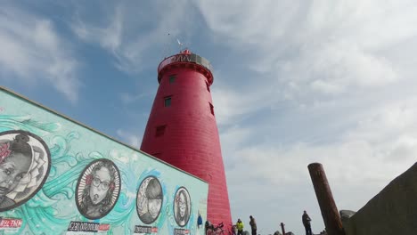 Tourists-Visiting-The-Poolbeg-Lighthouse-With-A-Lovely-Murals-On-Wal-In-Poolbeg,-Dublin,-Ireland