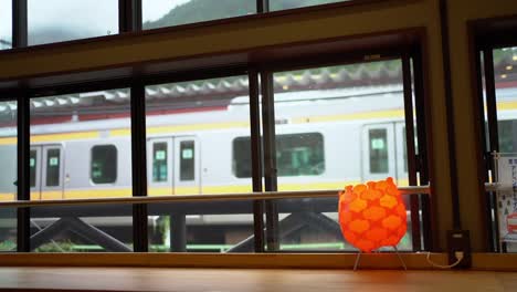Blick-Auf-Den-Japanischen-Zug,-Der-Von-Einem-Caféfenster-Auf-Der-Anderen-Seite-Des-Bahnhofs-Aus-Langsamer-Wird-Und-Zum-Stehen-Kommt