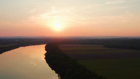 Gorgeous-orange-sun-setting-over-the-potomac-river-during-dusk-with-tranquil-river-water-drone-aerial