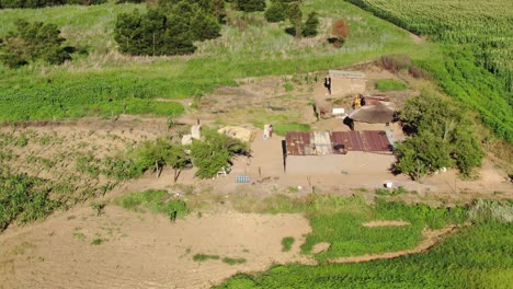 Orbiting-aerial-of-modest-rural-African-farm-house-with-family-in-yard