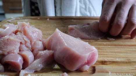 Hands-Cutting-Fresh-Chicken-Meat-Fillet-On-Wooden-Chopping-Board-In-The-Kitchen---close-up