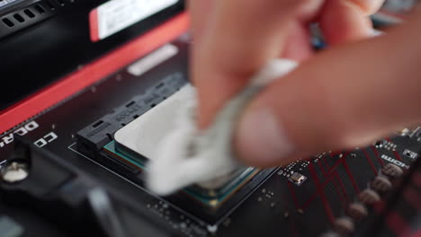 A-computer-repair-technician-installing-an-AMD-Ryzen-2400G-cpu-on-a-motherboard-and-cleaning-it-with-alcohol-before-applying-thermal-paste