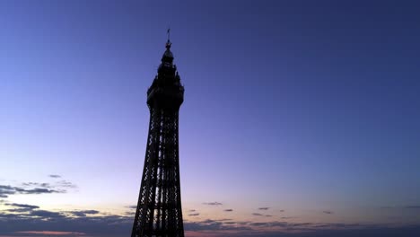 Blackpool-tower-aerial-view-high-night-coastal-seaside-resort-landmark-tourist-attraction-slow-lowering
