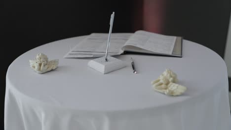 Gorgeous-and-clean-wedding-signing-table-set-up-with-white-cherub-angel-ornaments-and-a-stylish-white-pen-at-Next-Restaurant-in-Stittsville,-Ontario