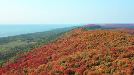 Riesiger-Wald-Mit-Wechselnden-Herbstfarben,-Landschaft-Mit-Sanften-Hügeln-Und-Seeufer-Am-Horizont---Drohnen-Luftaufnahme