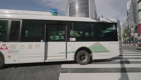 Diferentes-Vehículos-Que-Viajan-A-Través-Del-Cruce-De-Shibuya-Contra-Un-Edificio-Alto-En-Tokio,-Japón