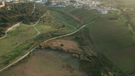 Camino-A-Través-Del-Pueblo-Medieval-Y-El-Castillo-En-El-Paisaje-De-Pradera-En-Obidos,-Portugal