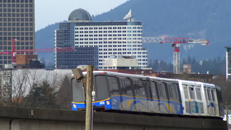 Expo-Line-Skytrain-Girando-En-Vía-Curva-Con-Grúas-Torre-Y-Edificios-En-El-Fondo-En-Vancouver,-Columbia-Británica,-Canadá