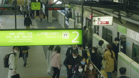 Menschen-In-Masken-Steigen-Während-Der-Coronavirus-Pandemie-Am-Bahnhof-Der-Yamanote-Linie-In-Tokio-In-Einen-Zug-–-Hoher-Winkel,-Zeitlupe