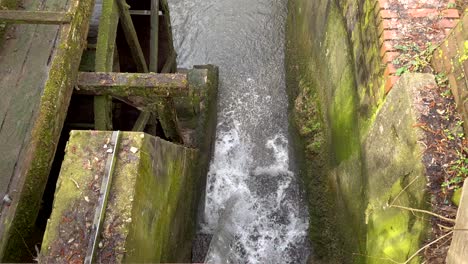 Moosiges-Wasserrad-Und-Fließender-Wasserfall,-Der-In-Einen-Kleinen-Bach-Stürzt