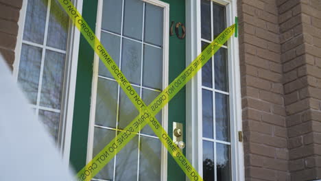 Yellow-crime-scene-do-not-cross-tape-across-front-door-of-house