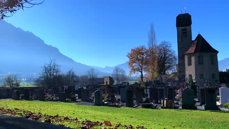 Old-Catholic-church-with-cemetery-or-graveyard-on-the-ground-with-blue-sky-and-mountain-in-the-background