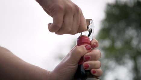 Opening-a-red-wine-bottle-outdoorÂ´s-with-two-hands-and-a-cork-screw
