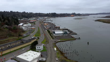 Aerial-flying-backwards-over-Oregon-Coast-Highway-and-old-wharf-buildings