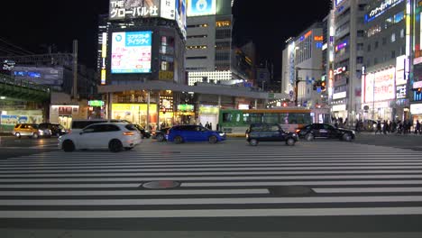 Wide-angle-of-crossing-outside-Omoide-Yokocho,-in-Shinjuku,-Tokyo,-with-traffic-passing-by-at-night