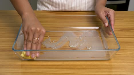 Married-female-rubbing-in-glass-cooking-tray-with-butter-for-cooking