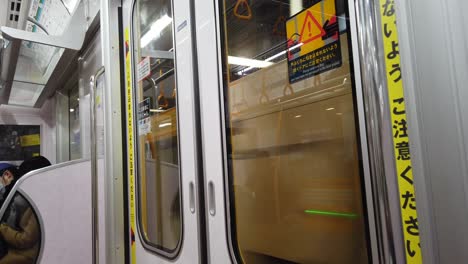 POV-Desde-El-Interior-Del-Tren-Subterráneo-Hasta-La-Puerta-Del-Tren-Mientras-Se-Mueve-En-Tokio,-Japón