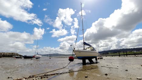 Fast-changing-overcast-weather-moving-above-moored-fishing-boats-on-low-tide-coast-sunny-conditions