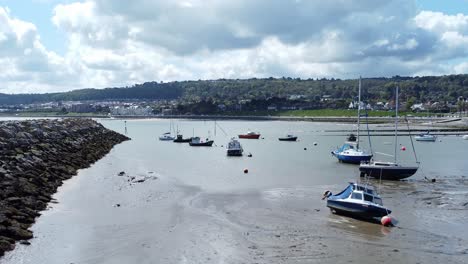 Aerial-view-moored-boats-on-Welsh-low-tide-seaside-breakwater-harbour-coastline