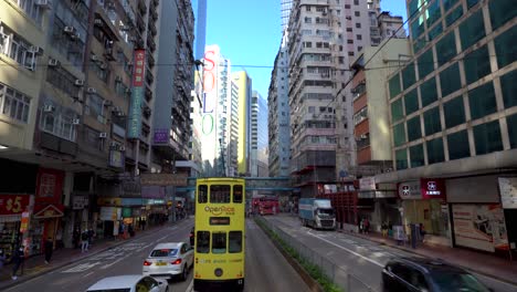 Causeway-Bay,-Hong-Kong,-Avenue-Traffic-in-Downtown-District,-Skyscrapers,-Cars-and-Public-Transportation,-View-From-Double-Decker-Tram-Front